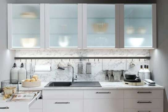 Weiße Hängeschränke mit integrierter Unterbauleuchte in einer modernen Burger Küche.